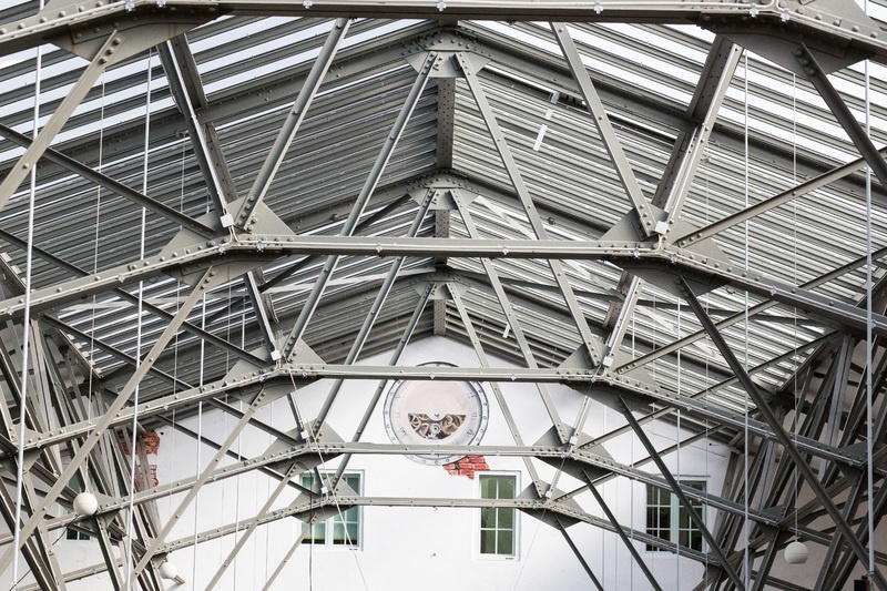 Upward shot of the interior of a school gymnasium with multiple steel structural connections